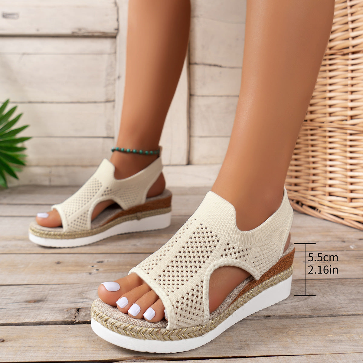 Beige open-toe sandals with a wooden wedge sole on a wooden floor.